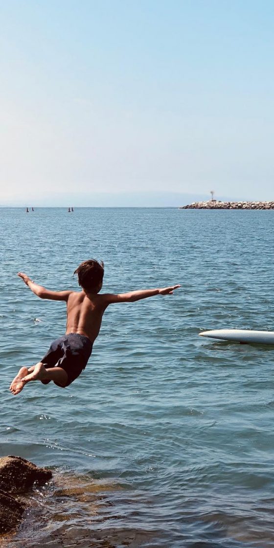 Junior Lifeguard diving off a cliff into the water to swim.